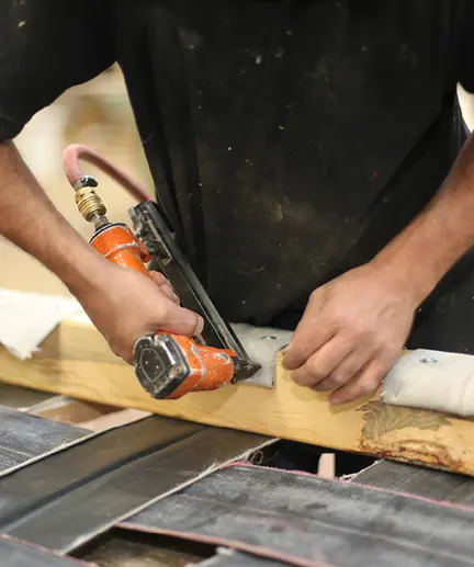 Monteur fixiert Stoffe an einer Holzleiste mit Hilfe einer Druckluftpistole.